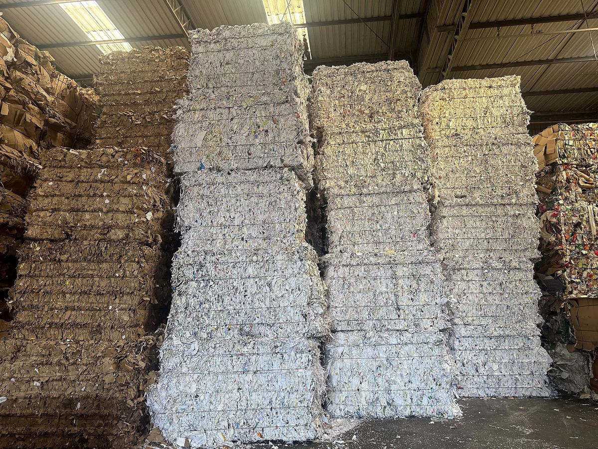 Fardos de aparas brancas ao lado de fardos de papelão